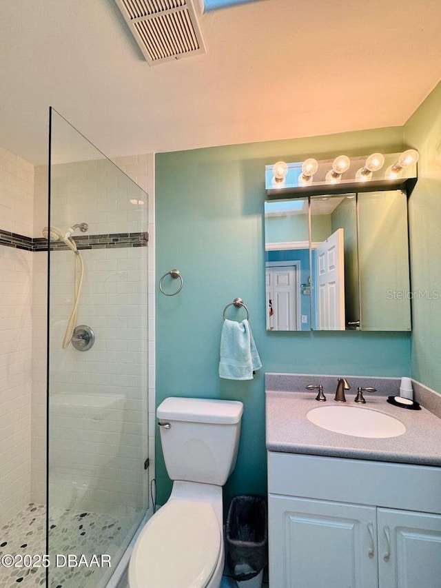 bathroom with a tile shower, vanity, and toilet