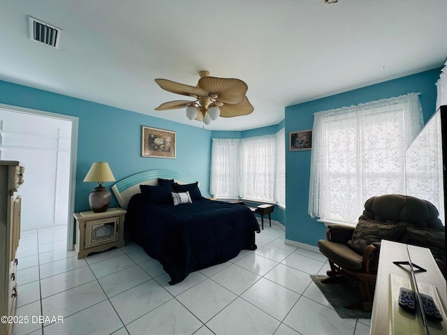 bedroom featuring ceiling fan, light tile patterned floors, and multiple windows