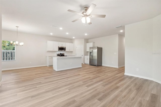 unfurnished living room featuring ceiling fan with notable chandelier and light hardwood / wood-style floors