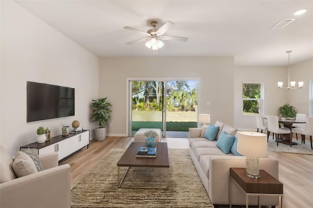 living room featuring light hardwood / wood-style flooring and ceiling fan with notable chandelier