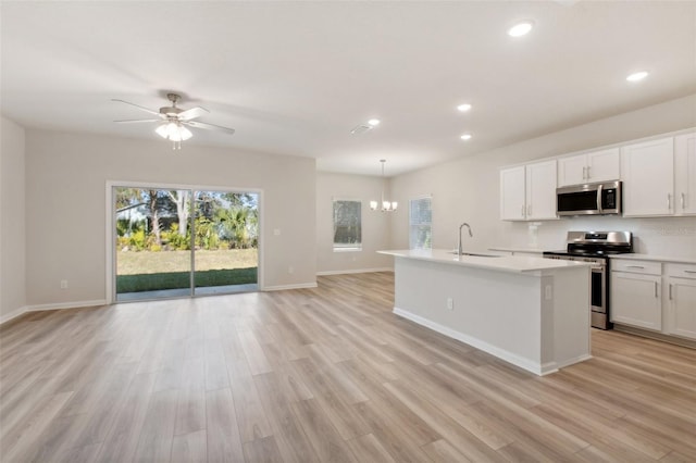 kitchen with pendant lighting, a center island with sink, white cabinets, ceiling fan with notable chandelier, and appliances with stainless steel finishes