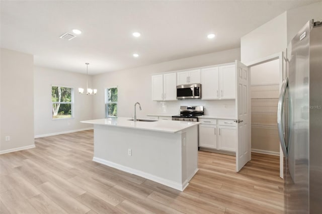 kitchen featuring white cabinets, a center island with sink, hanging light fixtures, and appliances with stainless steel finishes