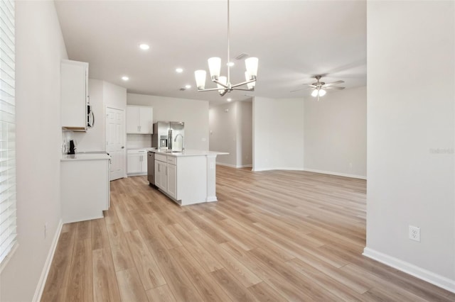 kitchen with white cabinets, appliances with stainless steel finishes, a center island with sink, and hanging light fixtures