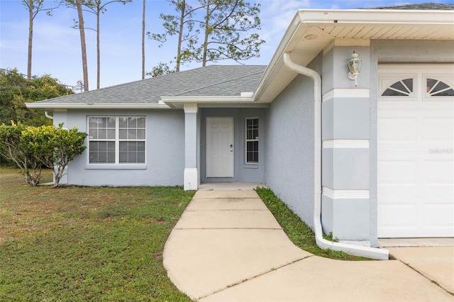 view of exterior entry featuring a lawn and a garage