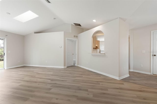 spare room with light hardwood / wood-style flooring and vaulted ceiling with skylight