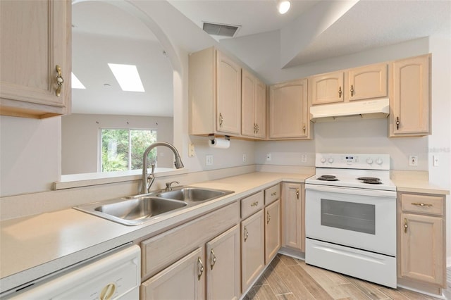 kitchen featuring white appliances, a skylight, light brown cabinetry, and sink