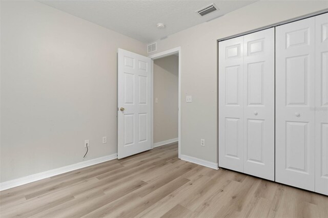 unfurnished bedroom with light hardwood / wood-style floors and a closet