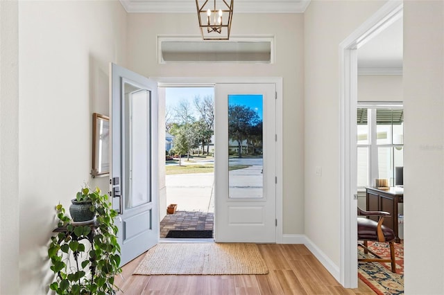 foyer entrance featuring a notable chandelier, light wood-type flooring, and ornamental molding