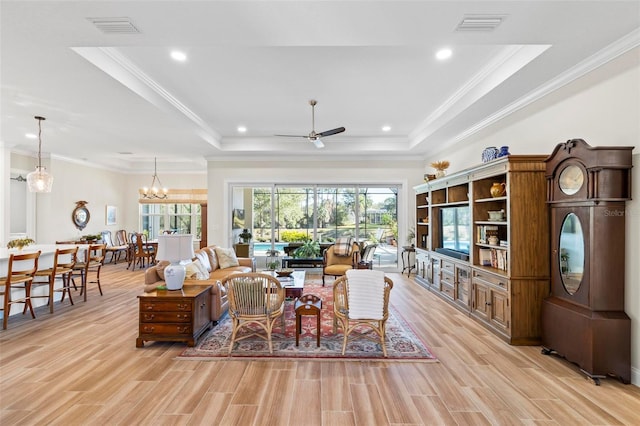 living room with crown molding, a raised ceiling, and ceiling fan with notable chandelier