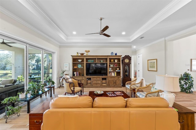 living room featuring ornamental molding, light hardwood / wood-style flooring, and a tray ceiling