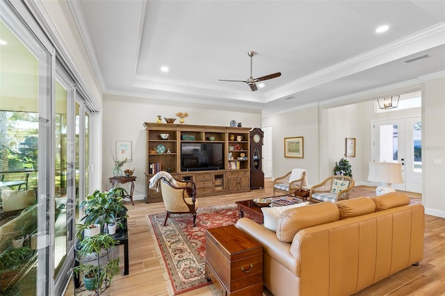 living room featuring ceiling fan, light wood-type flooring, french doors, and a tray ceiling