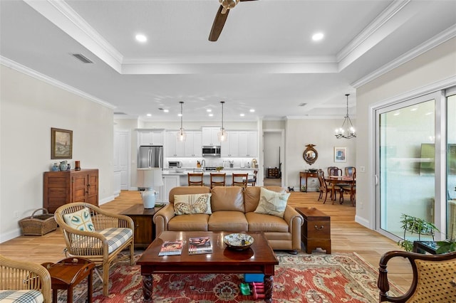 living room featuring light hardwood / wood-style floors, crown molding, a raised ceiling, and ceiling fan with notable chandelier