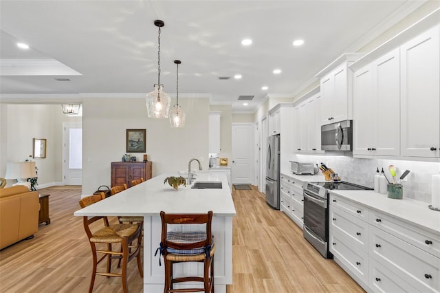 kitchen featuring pendant lighting, a center island with sink, a kitchen bar, appliances with stainless steel finishes, and sink