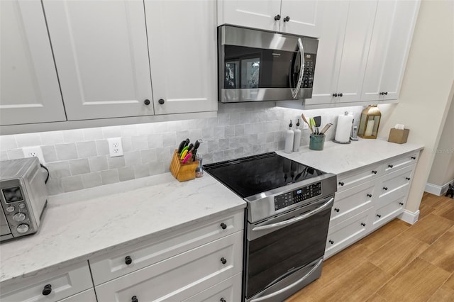 kitchen with appliances with stainless steel finishes, white cabinets, backsplash, and light stone countertops