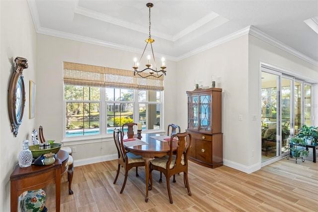 dining room with light hardwood / wood-style floors, ornamental molding, a raised ceiling, and a chandelier