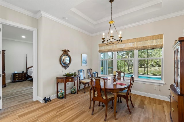 dining area featuring a raised ceiling, light wood-type flooring, crown molding, and an inviting chandelier