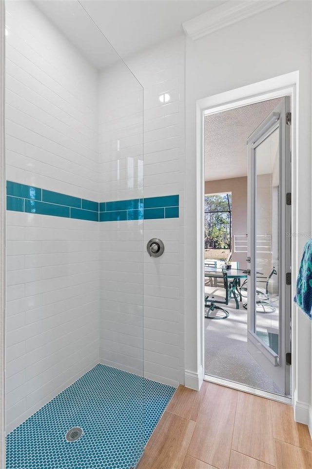 bathroom with a tile shower and ornamental molding