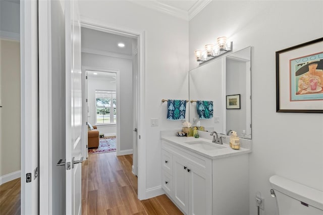 bathroom featuring ornamental molding, toilet, vanity, and wood-type flooring