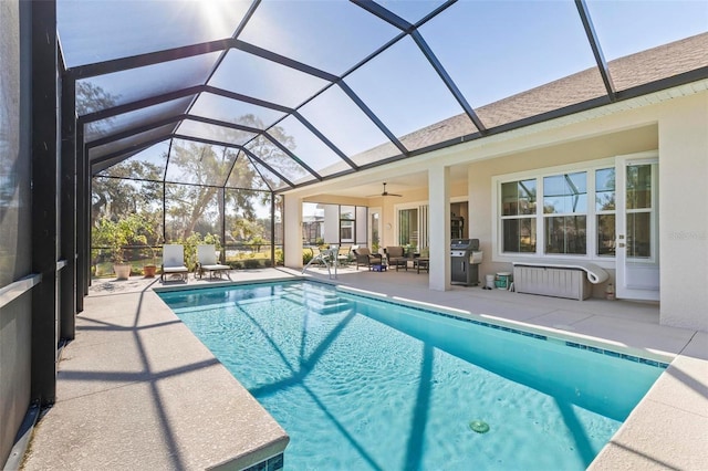 view of pool with ceiling fan, glass enclosure, and a patio