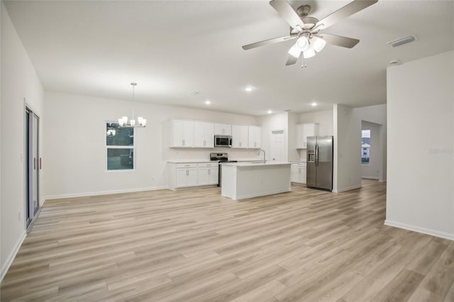 kitchen with a kitchen island with sink, white cabinets, ceiling fan with notable chandelier, decorative light fixtures, and stainless steel appliances