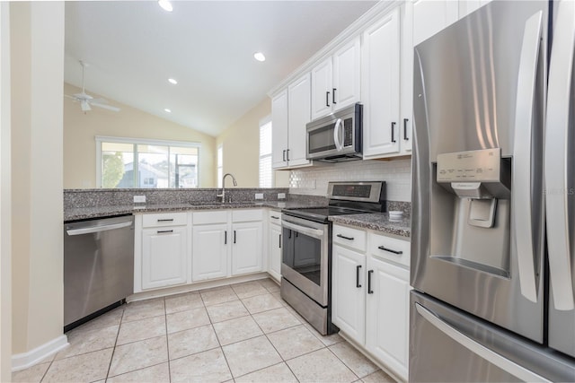 kitchen featuring lofted ceiling, backsplash, white cabinetry, appliances with stainless steel finishes, and sink