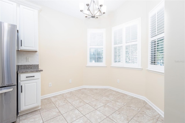 unfurnished dining area featuring an inviting chandelier and light tile patterned flooring