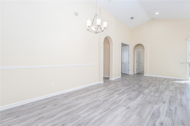 spare room featuring light wood-type flooring, an inviting chandelier, and high vaulted ceiling