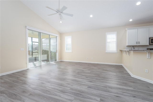 unfurnished living room with ceiling fan, a wealth of natural light, and light wood-type flooring