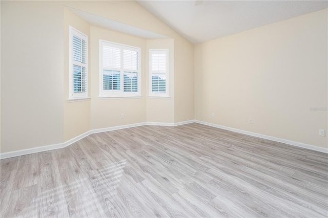 spare room featuring vaulted ceiling and light hardwood / wood-style floors