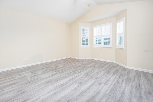 spare room featuring light wood-type flooring and vaulted ceiling