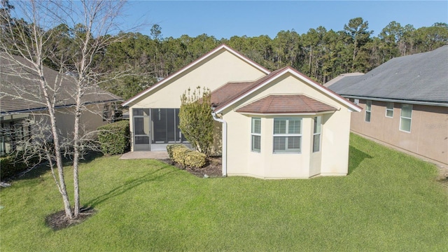 back of property featuring a sunroom and a lawn