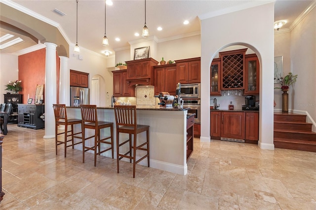 kitchen with ornate columns, stainless steel appliances, tasteful backsplash, a kitchen breakfast bar, and hanging light fixtures