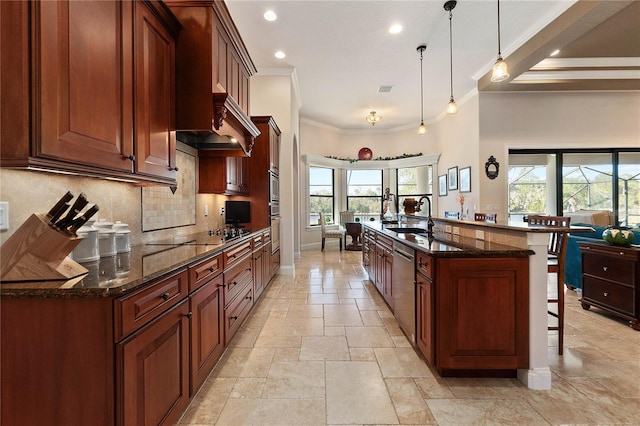 kitchen with a large island with sink, black electric stovetop, sink, hanging light fixtures, and a breakfast bar