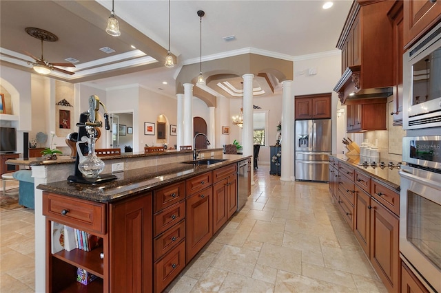 kitchen featuring sink, hanging light fixtures, stainless steel appliances, a large island, and ornate columns