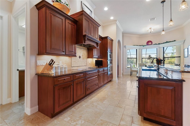 kitchen with pendant lighting, dark stone countertops, sink, backsplash, and oven