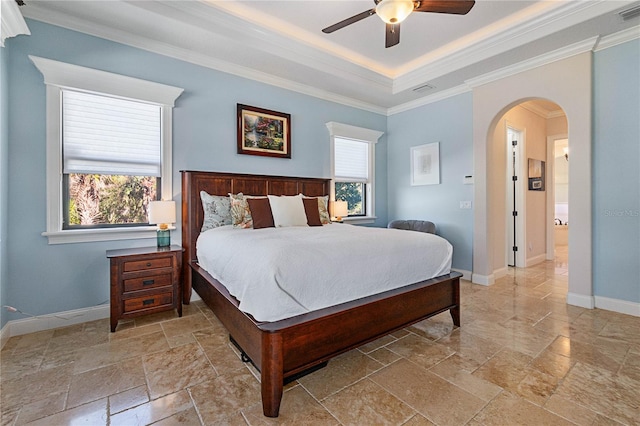 bedroom with ceiling fan, a tray ceiling, and ornamental molding