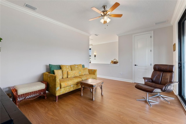 living room with ceiling fan, ornamental molding, and light hardwood / wood-style floors