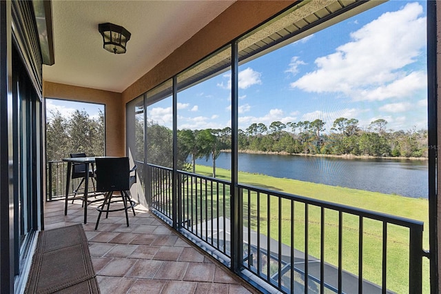 sunroom featuring a water view