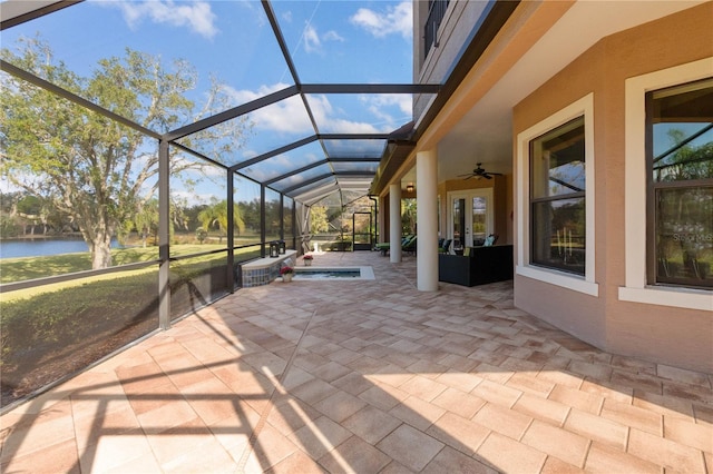 view of patio featuring a lanai, ceiling fan, and a water view