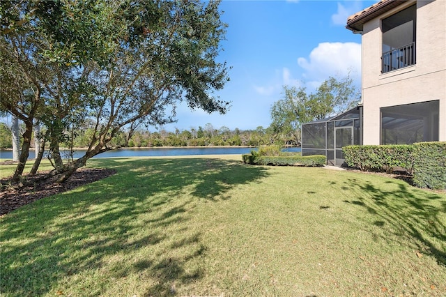 view of yard with a lanai and a water view