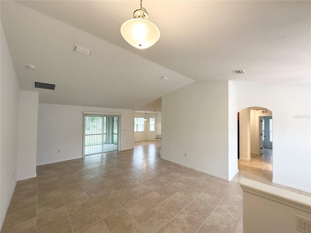 tiled spare room featuring lofted ceiling