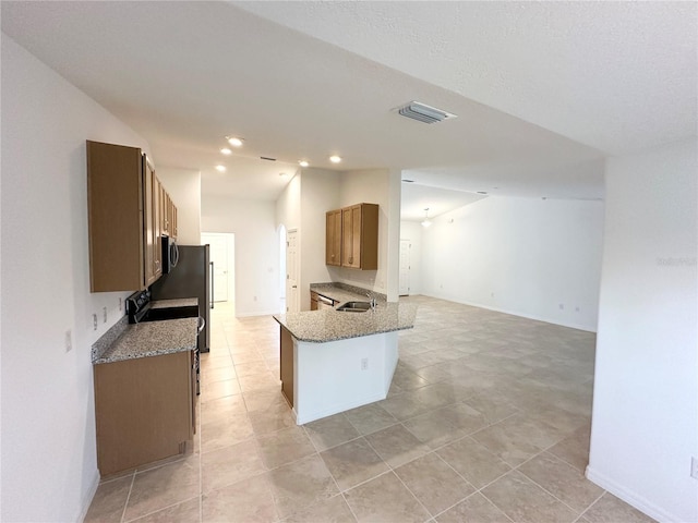 kitchen with sink, light stone counters, and kitchen peninsula