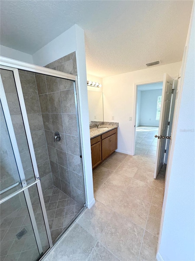 bathroom with vanity, a textured ceiling, and a shower with shower door