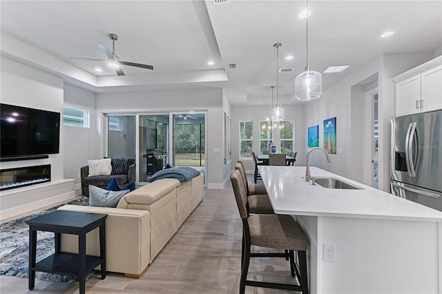 kitchen featuring sink, white cabinetry, hanging light fixtures, a center island with sink, and a breakfast bar