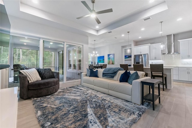 living room featuring ceiling fan with notable chandelier and a tray ceiling