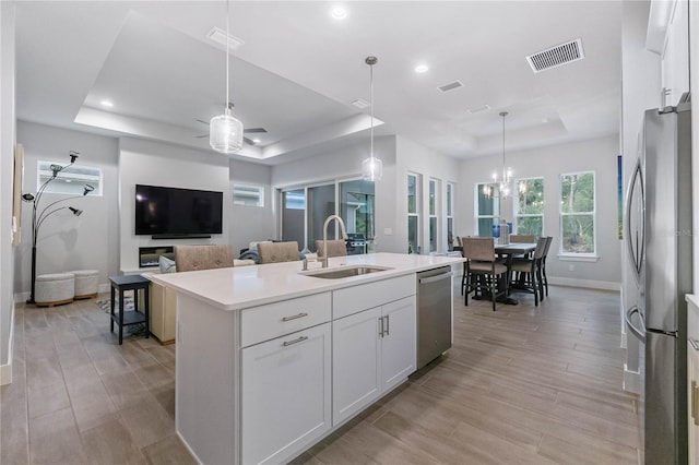 kitchen featuring stainless steel appliances, a raised ceiling, sink, and white cabinets