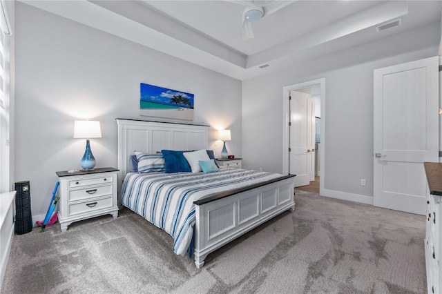 carpeted bedroom featuring a raised ceiling and ceiling fan