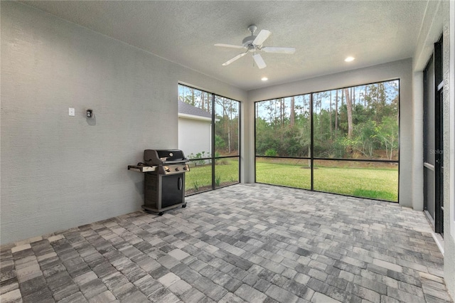 unfurnished sunroom featuring ceiling fan