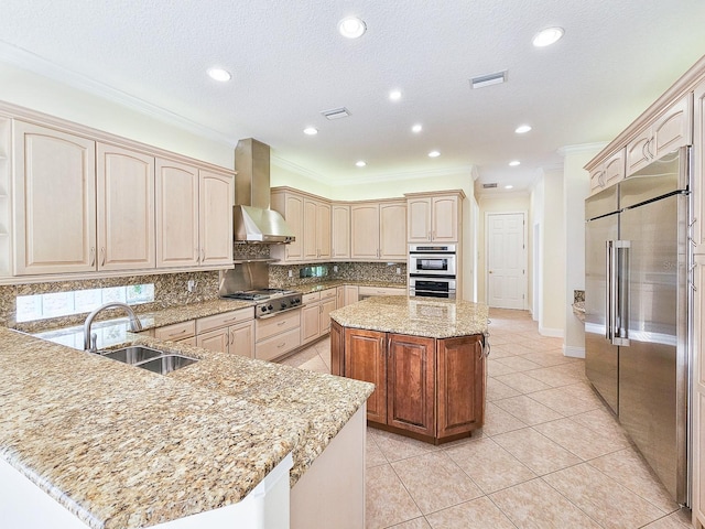 kitchen with a kitchen island, appliances with stainless steel finishes, sink, light stone counters, and wall chimney exhaust hood