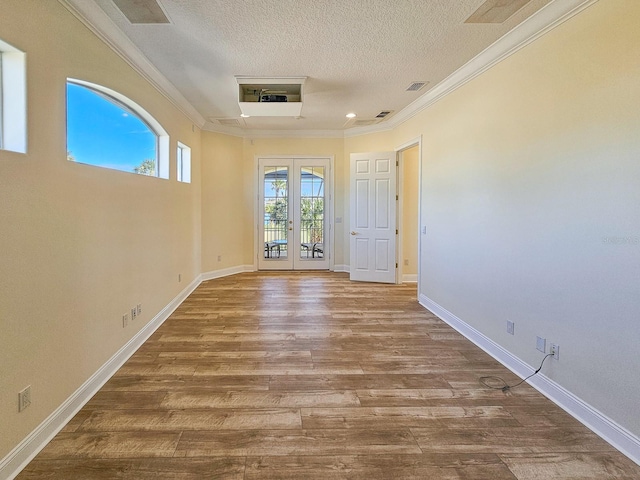 unfurnished room featuring french doors, ornamental molding, hardwood / wood-style floors, and a textured ceiling